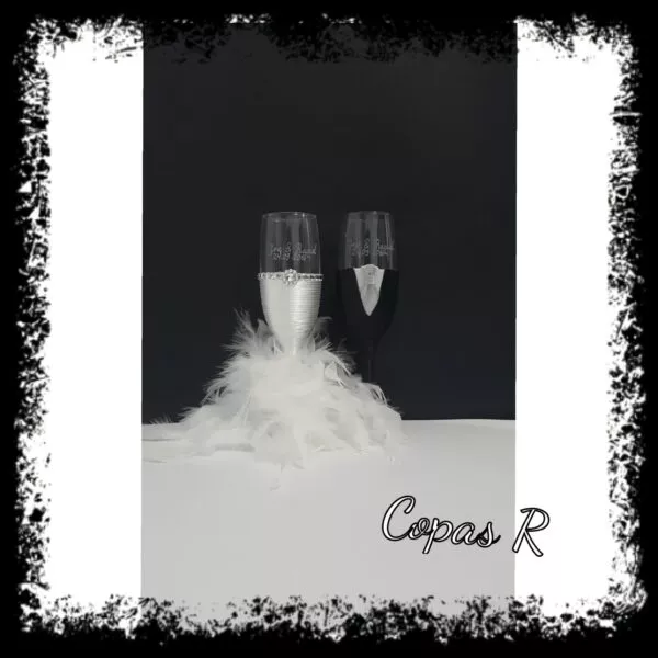 Copas de novios personalizadas en blanco con boa de plumas decorando la base
