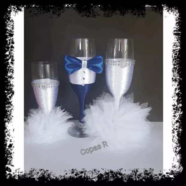 Copas de novios personalizadas en azul con pajarita y copas de novia blancas con pedrería y plumas