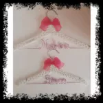 Perchas infantiles blancas con perlas y lazo fucsia