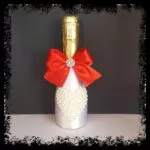 Botella de cava decorada plateada con lazo rojo y corazón de perlas