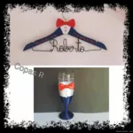 Percha infantil azul marino con pajarita roja y copa a juego