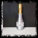Botella de cava decorada con encaje plateado y broche