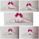 Perchas blancas con lazo fucsia y nombre en alambre
