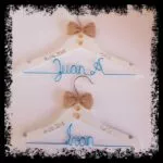 Perchas infantiles blancas con lazo de yute y nombre azul
