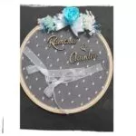Bastidor porta alianzas con flores azules y nombres Rimona y Claudiu