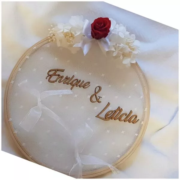Bastidor porta alianzas de madera con flores blancas y rosa roja preservada y nombres en letras de madera