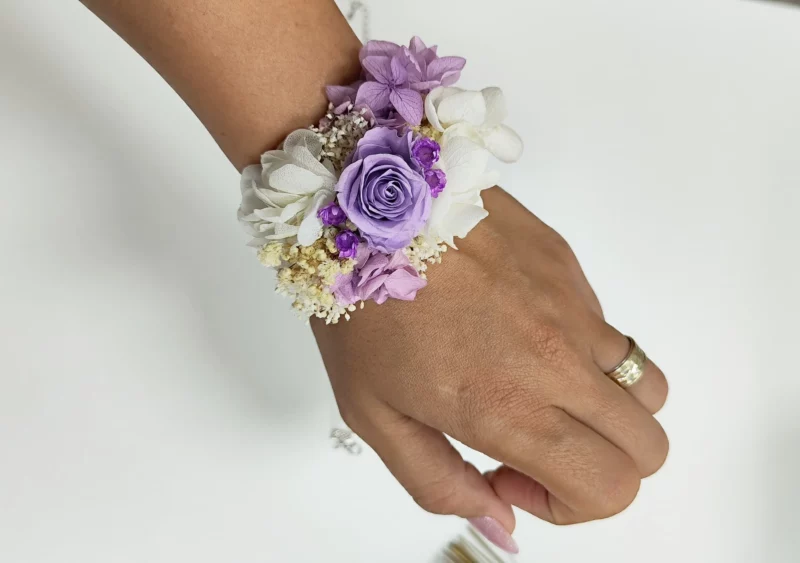 Pulsera para damas de honor con flores preservadas en tonos morados, blancos y beige. Un accesorio elegante y personalizado para bodas.