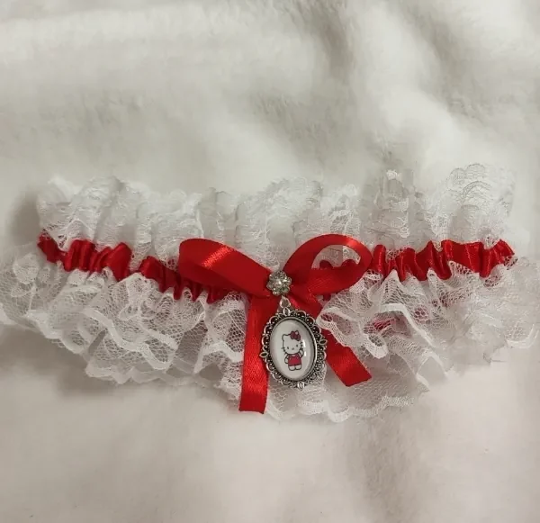 Liga de novia con encaje blanco, lazo rojo e incluye camafeo de Hello Kitty. Ajustable cualquier talla.