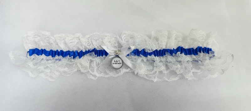 Liga de novia personalizada con encaje blanco, cinta azul y camafeo personalizable.