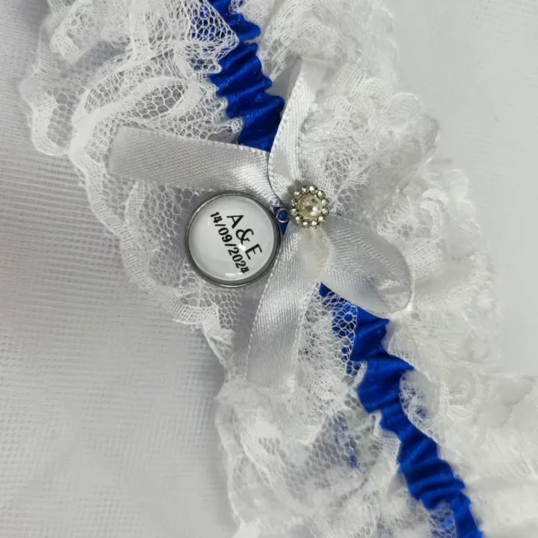 Liga de novia personalizada con encaje blanco, cinta azul y camafeo personalizable.