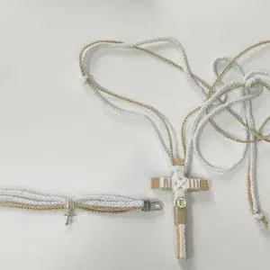 Conjunto de comunión con cruz de madera e hilo blanco con detalles dorados, e incluye pulsera a juego con colgante de cruz.