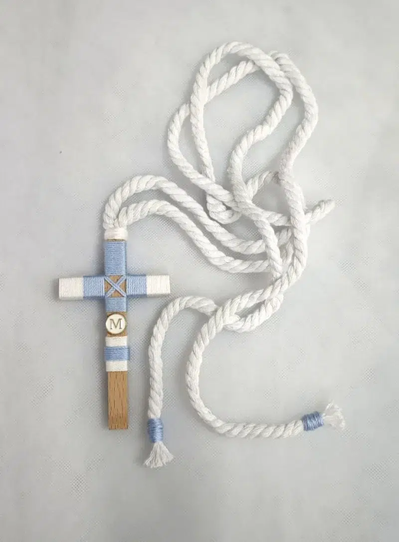 Cruz de comunión en madera con hilo azul y blanco, inicial personalizada y cordón retorcido blanco.