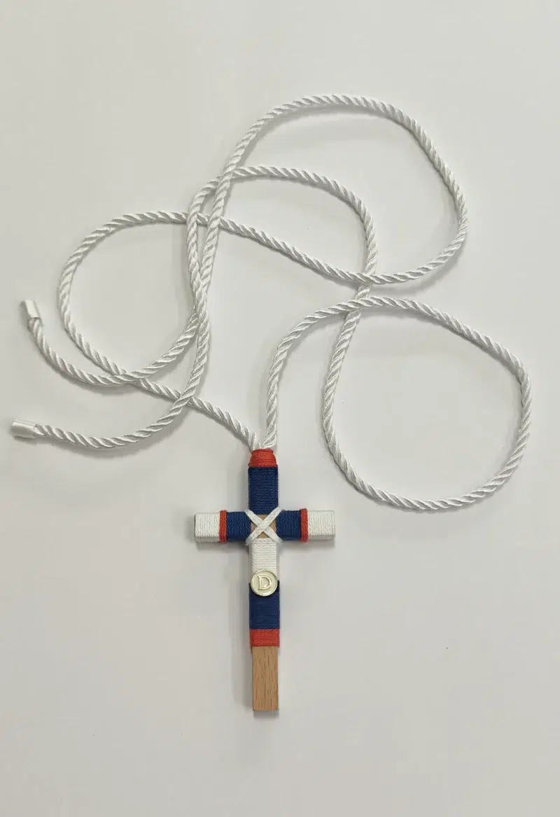 Cruz de comunión en madera con hilo azul, blanco y rojo, inicial personalizada y cordón retorcido blanco.