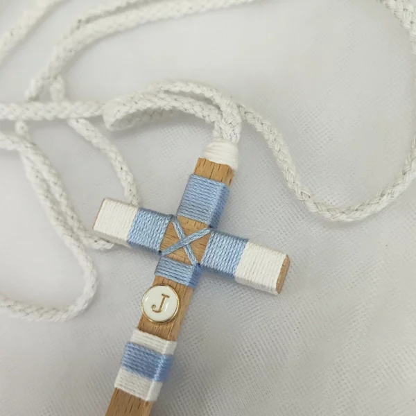Cruz de comunión para niño en madera con hilo azul y blanco, inicial personalizada y cordón trenzado.