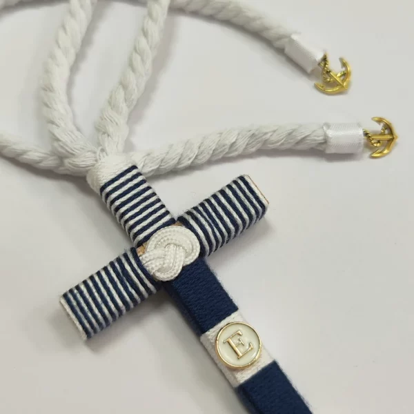 Cruz de comunión en madera con hilo azul marino y blanco, inicial personalizada y cordón retorcido con detalles de anclas doradas.