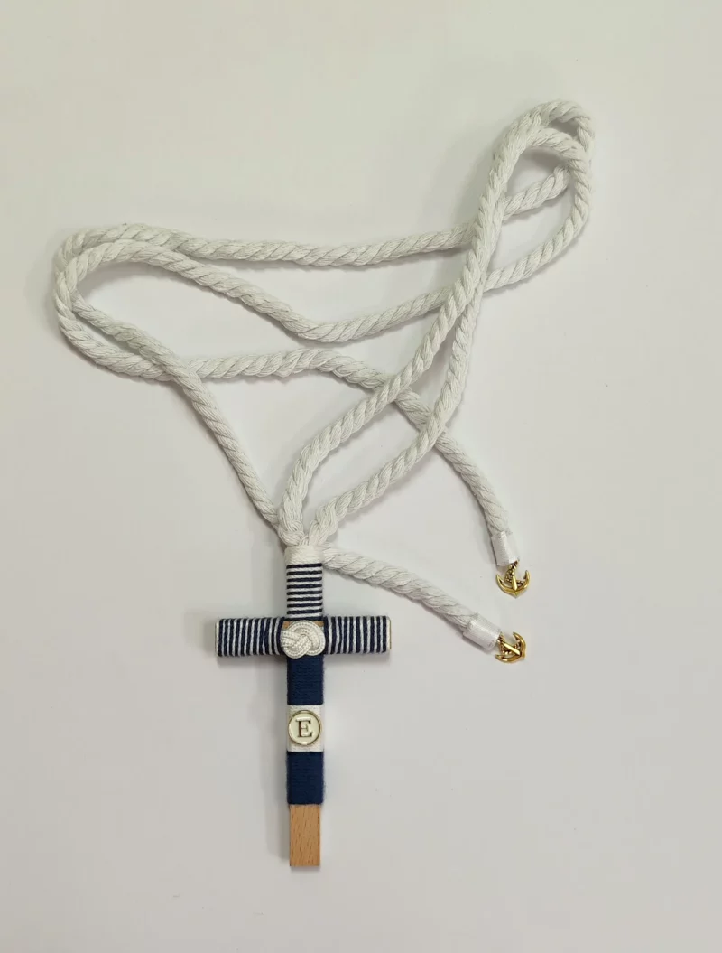 Cruz de comunión en madera con hilo azul marino y blanco, inicial personalizada y cordón retorcido con detalles de anclas doradas.