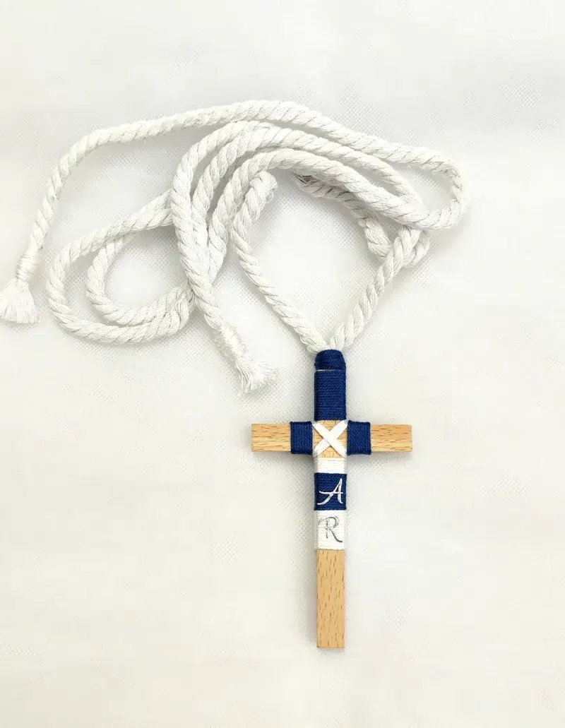 Cruz de comunión en madera con hilo azul marino y blanco, inicial personalizada y cordón retorcido blanco.