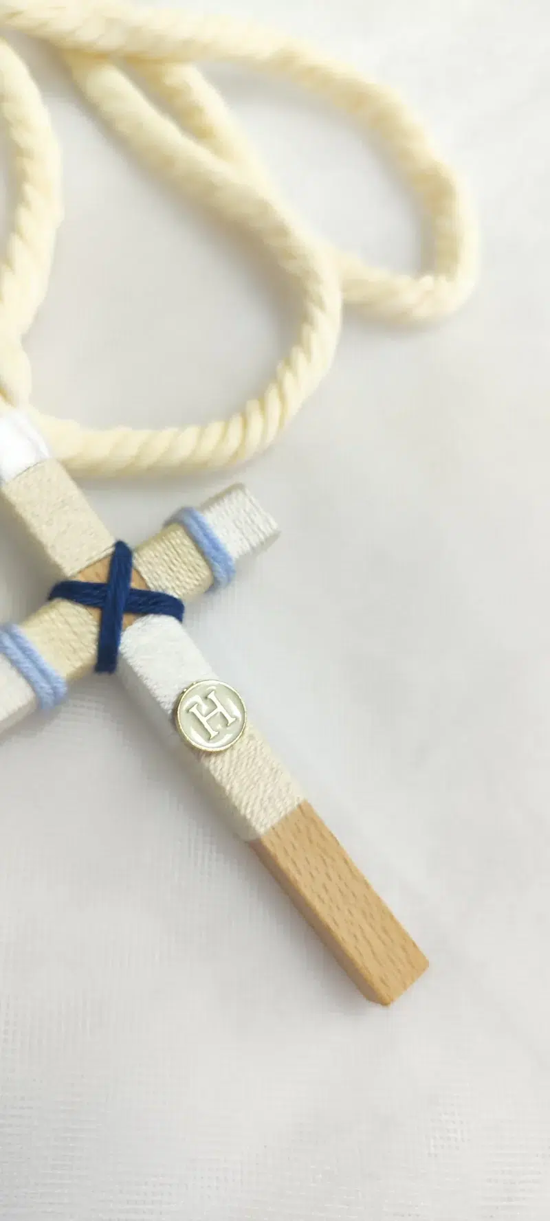 Cruz de comunión en madera con hilo beige, blanco y azul, inicial personalizada y cordón retorcido en color marfil.