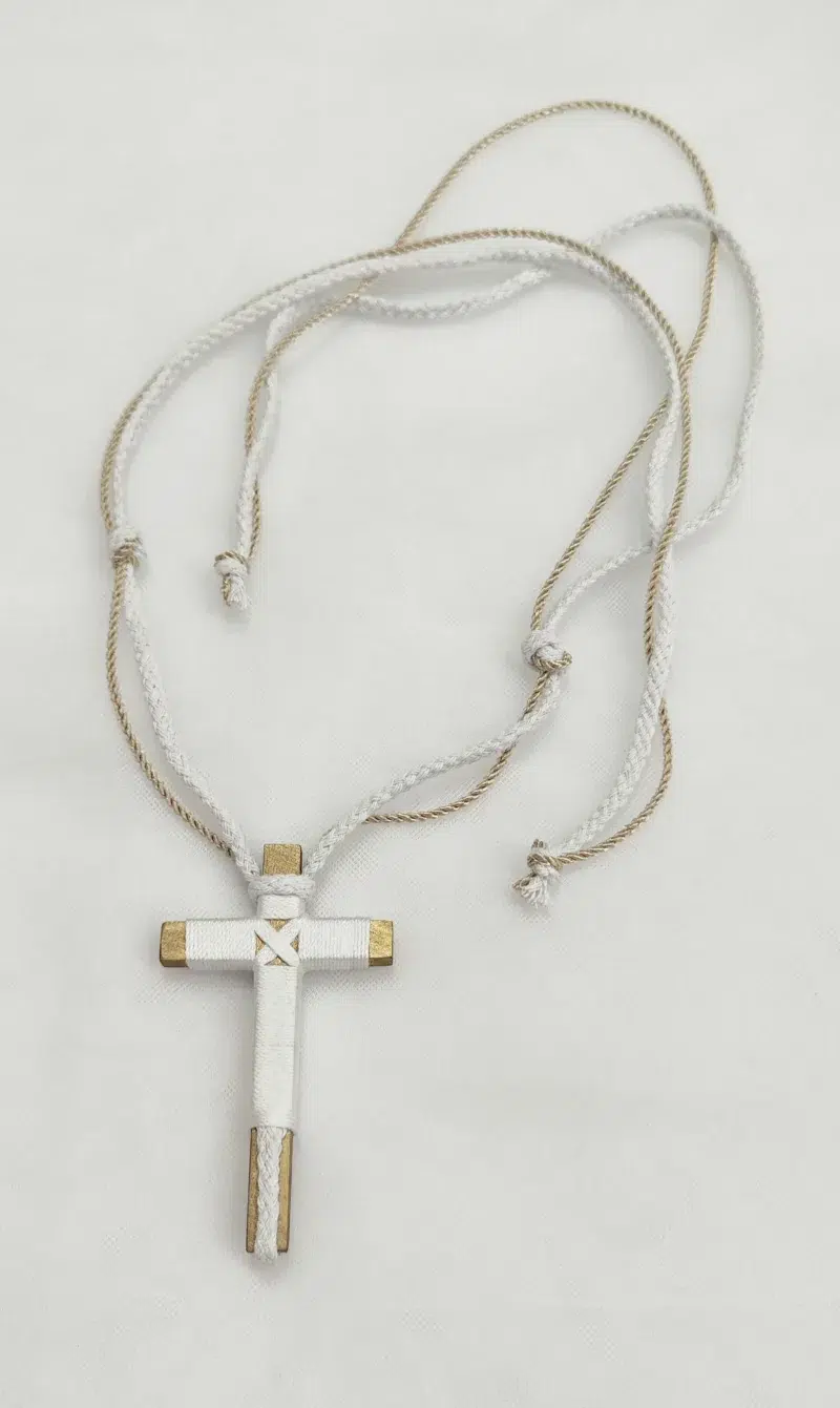 Cruz de comunión en madera con hilo blanco y detalles dorados, cordón ajustable en blanco y beige.