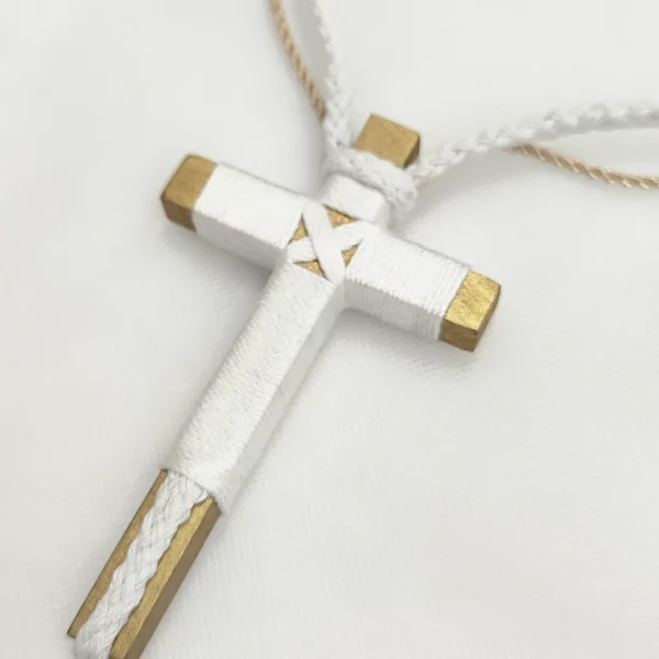 Cruz de comunión en madera con hilo blanco y detalles dorados, cordón ajustable en blanco y beige.