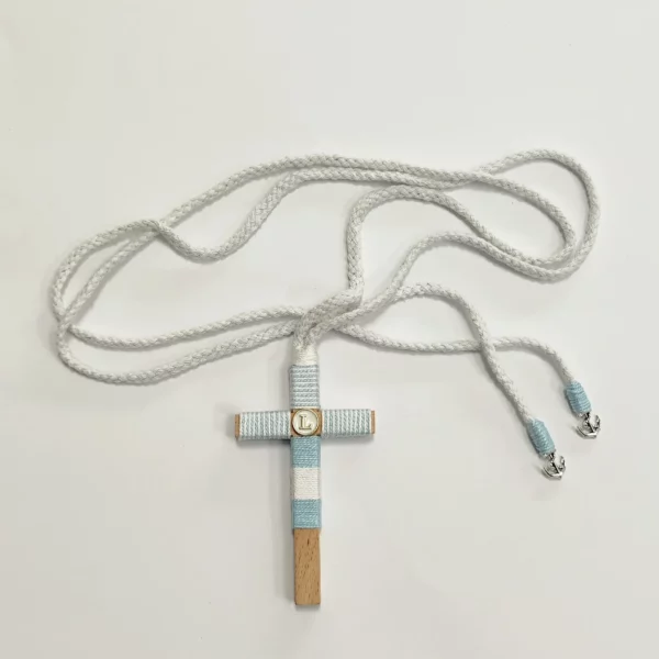 Cruz de comunión en madera con hilo azul turquesa y blanco, inicial personalizada y cordón trenzado con anclas plateadas.