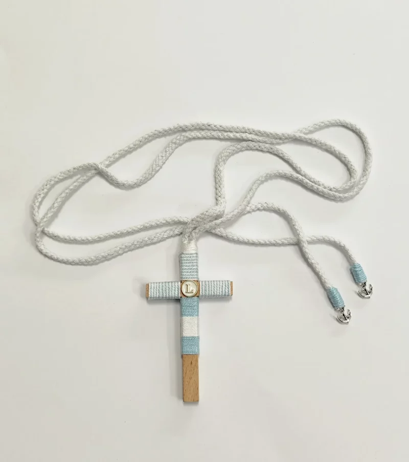 Cruz de comunión en madera con hilo azul turquesa y blanco, inicial personalizada y cordón trenzado con anclas plateadas.