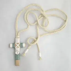 Cruz de comunión en madera con hilo verde y blanco, inicial personalizada y cordón trenzado beige.