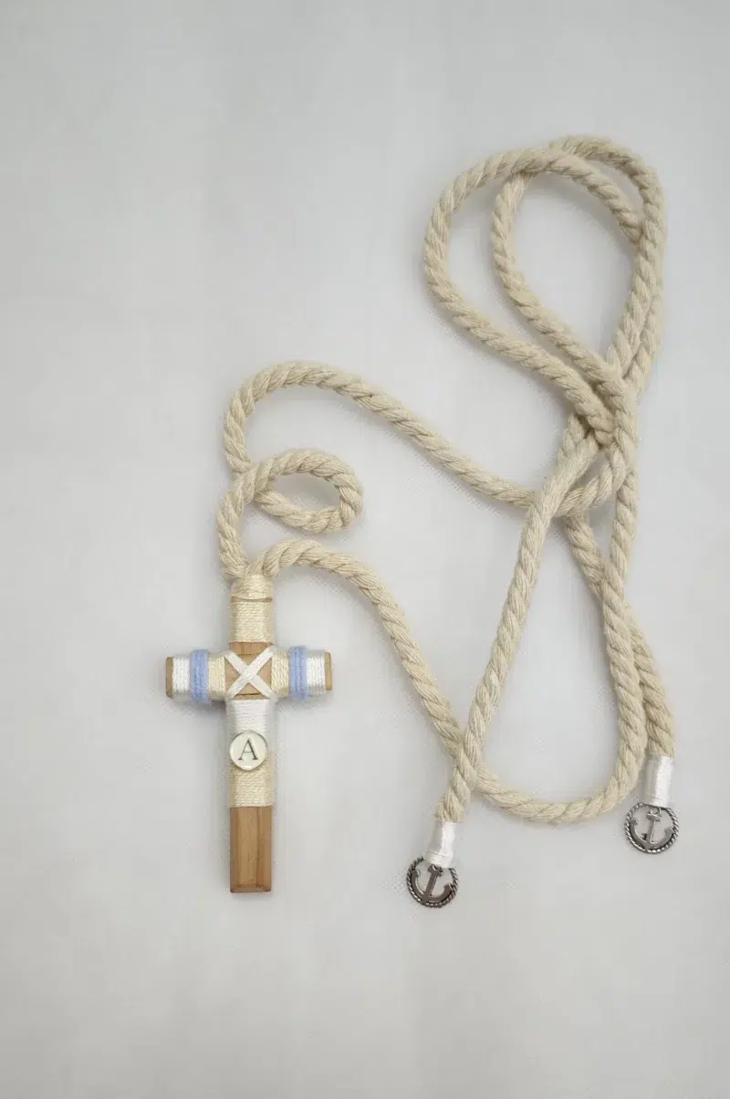 Cruz de comunión en madera con inicial personalizada y cordón ajustable.