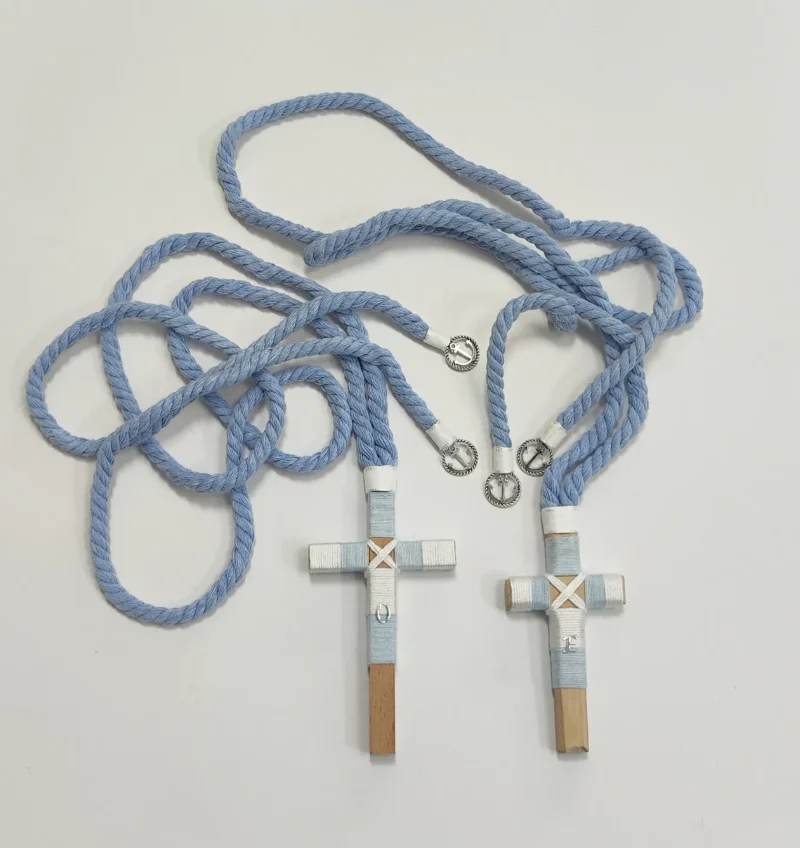 Conjunto de cruces de comunión en madera con hilo celeste y blanco, iniciales personalizadas y cordón trenzado azul con detalles plateados.