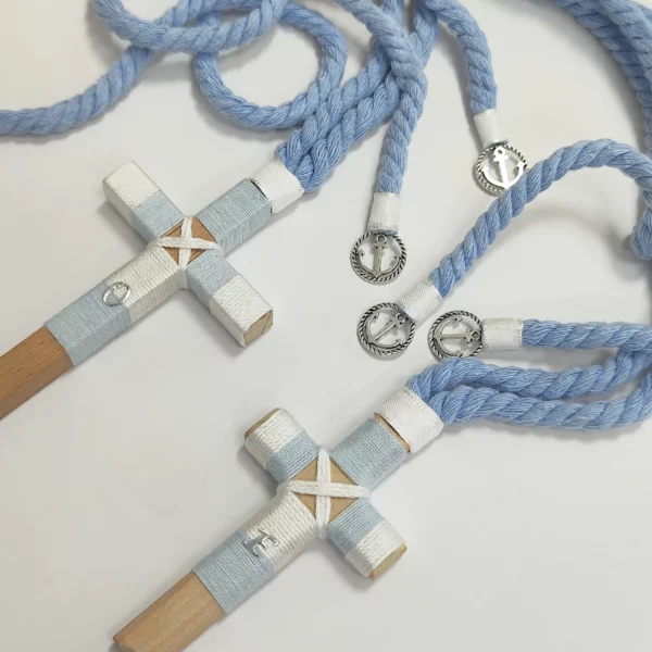Conjunto de cruces de comunión en madera con hilo celeste y blanco, iniciales personalizadas y cordón trenzado azul con detalles plateados.