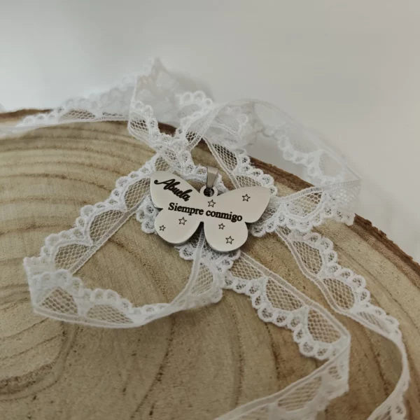 Medalla mariposa para ramo de novia en acero inoxidable, grabada a láser con «Abuela» y «Siempre conmigo» y puntilla blanca.