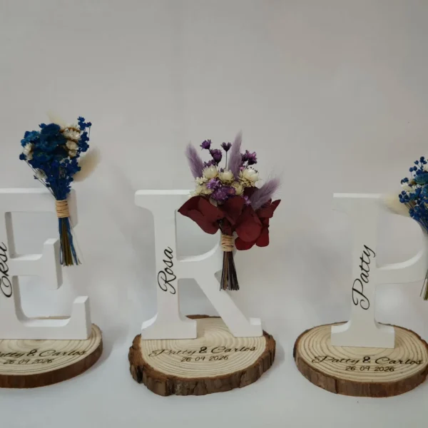 letras blancas de madera con nombres de invitadas flores preservadas y base grabada con los nombres de los novios y la fecha de la boda