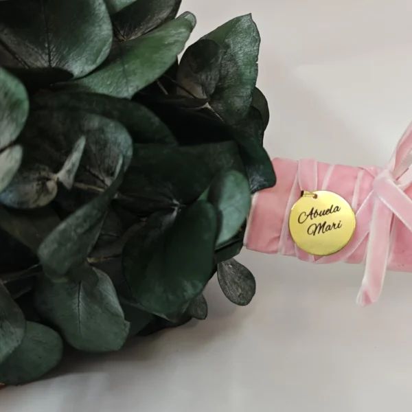 medalla dorada de acero inoxidable grabada a laser con abuela mari colgada del ramo de novia con lazo de terciopelo rosa