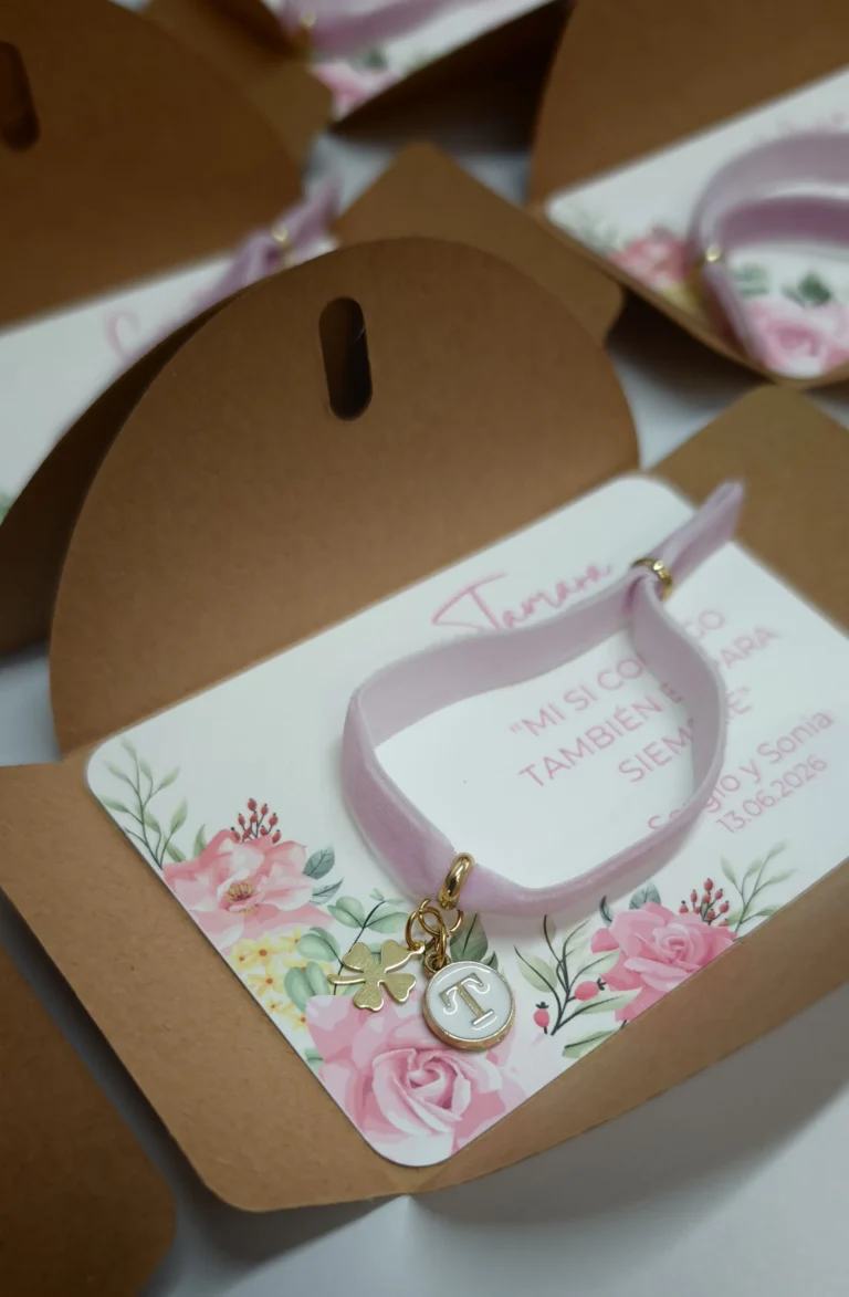 pulsera elástica de terciopelo rosa con inicial dorada y trébol sobre tarjeta personalizada con sobre kraft