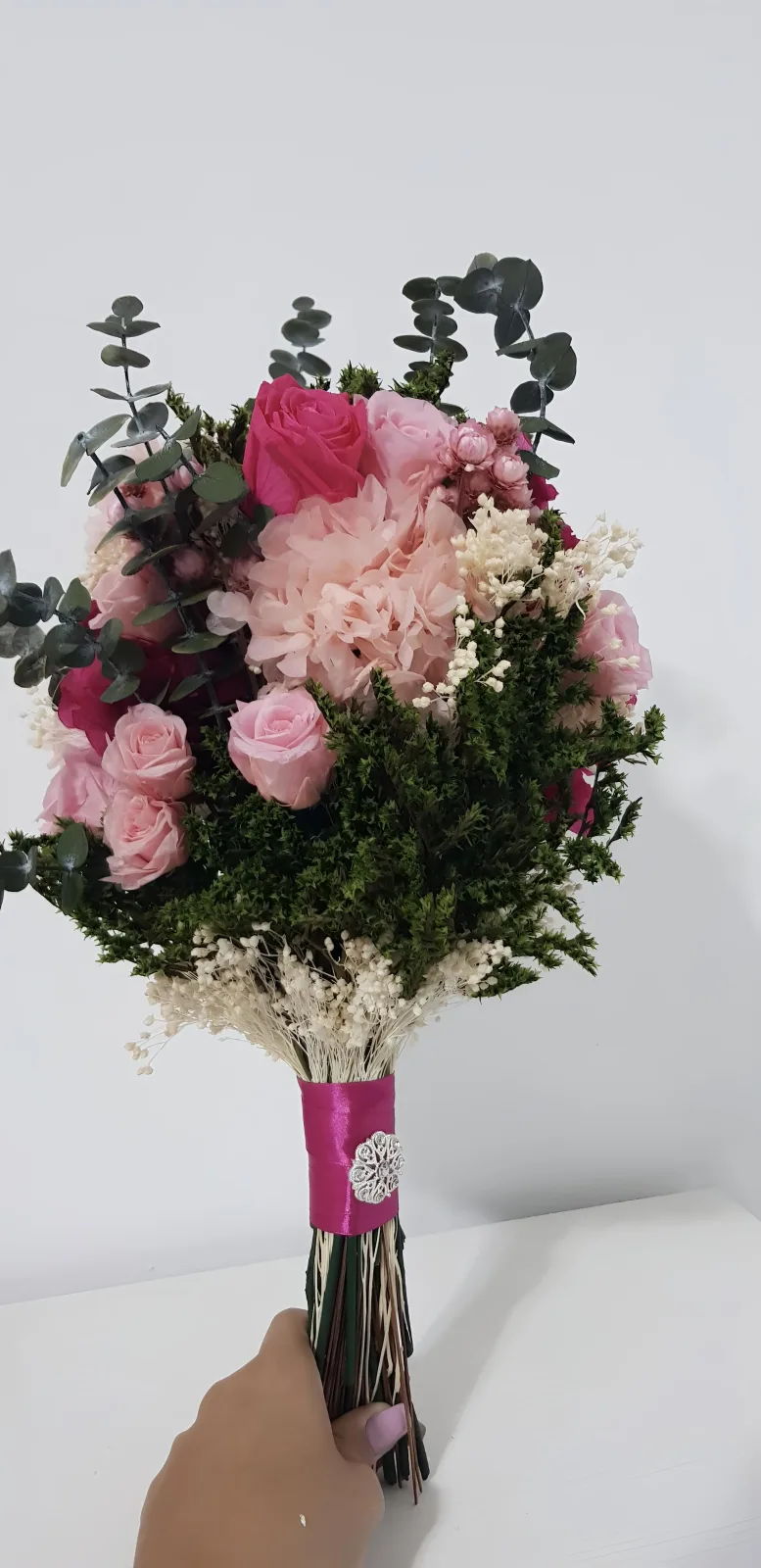 Ramo de novia con hortensias y rosas preservadas en rosa claro y fucsia, con cinta de raso fucsia y broche plateado